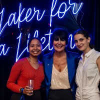 Two girls on stage posing with President Mantella.